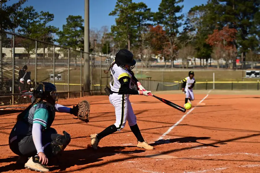 Softball batter swinging with the catcher behind her