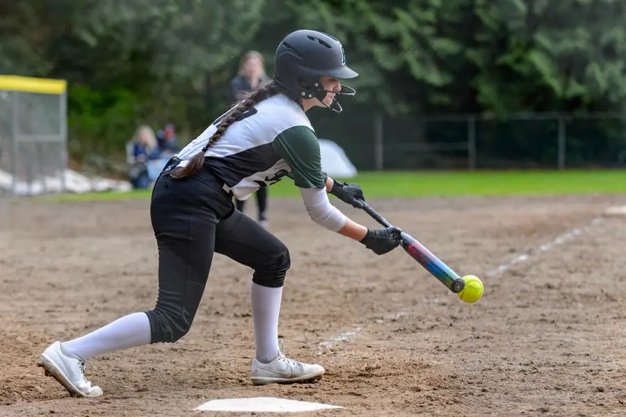 Softball player in a batting helmet laying down a bunt