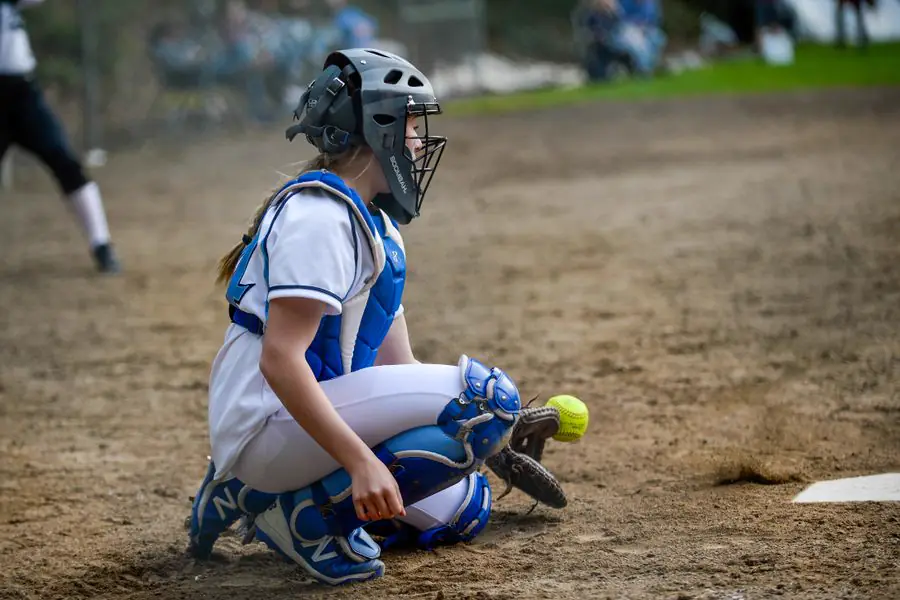 Young softball catcher crouched behind home plate