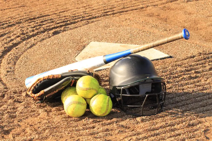 Softball bat, balls, batting helmet and glove on home plate